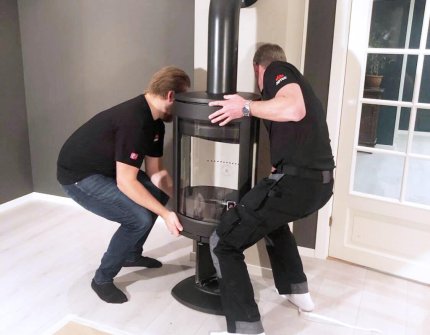 Two men mounting a Jøtul wood stove