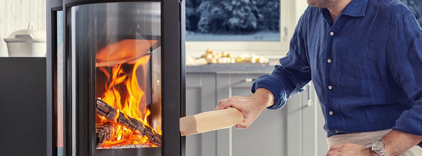 Man put wood in fireplace. Photo.