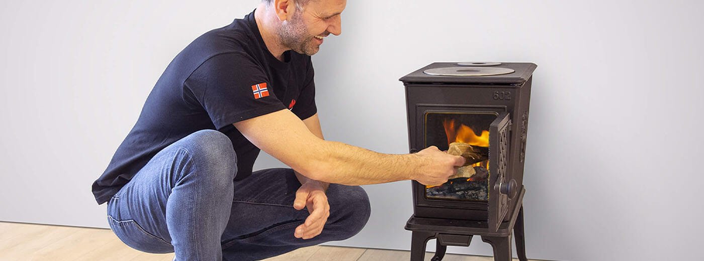 man puts wood in the wood stove jøtul f 602